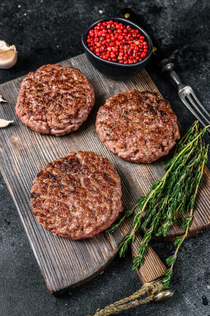 BBQ grilled beef meat patties for burger from mince meat and herbs on a wooden board.